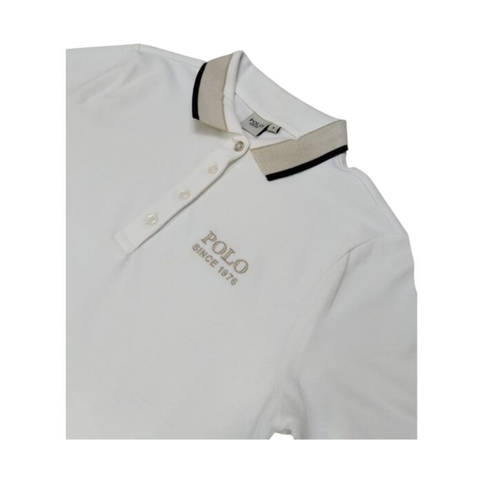 1014 6 C | The Polo Golfer Dress Macey Tipped Off White is a timeless blend of sporty elegance and refined sophistication, featuring a classic polo silhouette with contrast tipping along the collar and sleeve edges for a polished yet effortless look. Crafted from a high-quality cotton blend, this dress offers exceptional comfort with a soft, breathable feel and just the right amount of stretch, ensuring ease of movement while maintaining a flattering, tailored fit suitable for various occasions. Whether paired with sneakers for a casual day out or dressed up with loafers and a blazer for a chic, business-casual ensemble, this versatile piece is designed for durability, retaining its pristine appearance and impeccable craftsmanship even after multiple wears and washes.