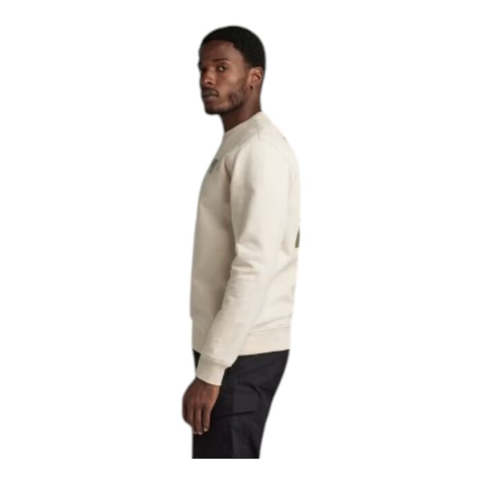 144 30 B | The G-Star RAW Flight Deck Back Graphic Sweater in Beige is a stylish and versatile piece crafted from 100% organic cotton, offering a soft, breathable feel while promoting sustainability in fashion. Featuring a classic ribbed round neckline, a straight fit for a comfortable yet modern silhouette, and a bold flight deck-inspired graphic on the back, this sweater effortlessly blends contemporary design with timeless appeal. Designed with ribbed cuffs and hem for a structured finish, this high-quality piece is easy to maintain with simple care instructions, making it a durable and eco-conscious addition to any wardrobe.